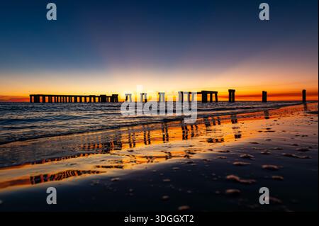 Vivace tramonto colorato sul vecchio molo di Fort Myers con un bel riflesso sull'acqua, Florda Foto Stock