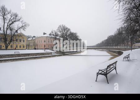 Panchine, edifici storici sul ghiacciato fiume Aurajoki, Turku invernale o Abo svedese, Varsinais-Suomi, Finlandia Foto Stock