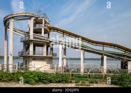Una foto completa di una complessa torre di scivoli d'acqua con scale a spirale e ingressi multipli per scivoli. La struttura è alta contro un cielo blu, silenziosa Foto Stock