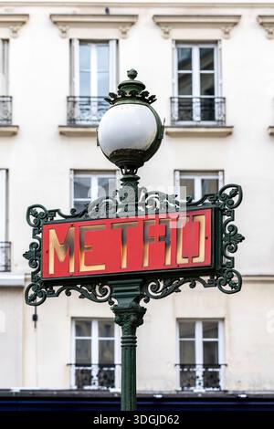 Un bellissimo cartello della metropolitana Art Nouveau con ornati lavori in ferro, adagiato sull'elegante facciata di un classico edificio di appartamenti parigino. Un concetto di tempo Foto Stock
