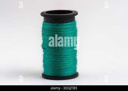 Bobina di filo verde isolata su primo piano su sfondo bianco Foto Stock