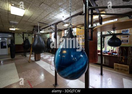 Una sezione di allenamento di pugilato in una comunità rurale con risorse limitate. Un grande sacchetto di punzonatura riempito d'acqua blu è appeso, sacchetti di punzonatura neri riempiti di sabbia A. Foto Stock