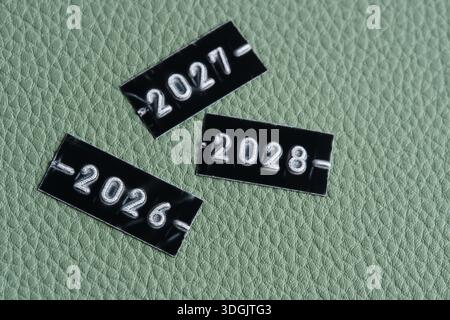 Etichette nere con gli anni 2026, 2027 e 2028 su sfondo verde in pelle. Concetto di anno nuovo Foto Stock