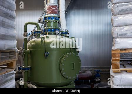 Pompa a camera pneumatica verde utilizzata per il trasporto di prodotti sfusi in una fabbrica moderna. L'apparecchiatura industriale è collegata a un pannello di controllo e a surr Foto Stock