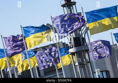 Le bandiere nazionali dell'Ucraina e dell'Unione europea ondeggiano insieme su pali metallici contro il cielo blu, a simboleggiare la forte alleanza politica e il futuro Foto Stock