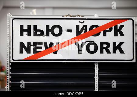 Un cartello stradale danneggiato da schegge che segna l'uscita da Niu-York (New York) a Donetsk, Ucraina. Il nome della città, scritto in ucraino e inglese, è cros Foto Stock
