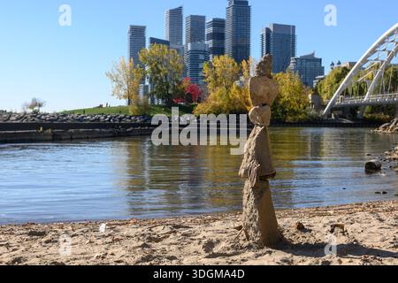 Rock Cairn mostra un perfetto equilibrio e tranquillità su una spiaggia sabbiosa con alberi autunnali, acque calme e il moderno skyline di Etobicoke, Toronto, in ba Foto Stock