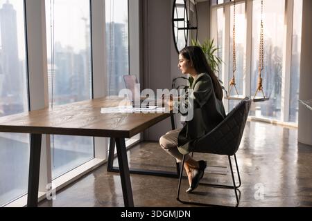 Giovane donna professionista ispanica che lavora in un ufficio confortevole Foto Stock