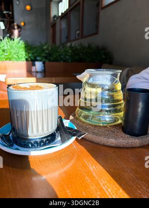 Tazza di caffè e teiera con tè verde servito su un tavolo di legno nel caffè. Immagine dei contenuti dei social media. Foto Stock