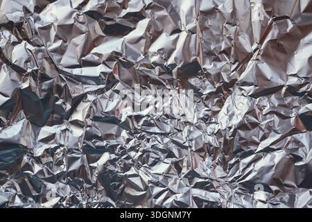 Lamina di alluminio increspata che mostra una texture metallica lucida e motivi astratti Foto Stock