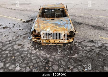 Un'auto bruciata abbandonata viene vista in un parcheggio. Foto Stock