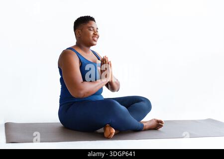 La donna pratica Yoga in uno studio con sfondo chiaro durante il giorno Foto Stock