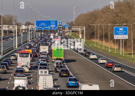 Traffico intenso sull'autostrada A2 olandese nei pressi di Utrecht con cartelli stradali blu che indicano le indicazioni per Amsterdam durante il giorno. Utrecht Foto Stock