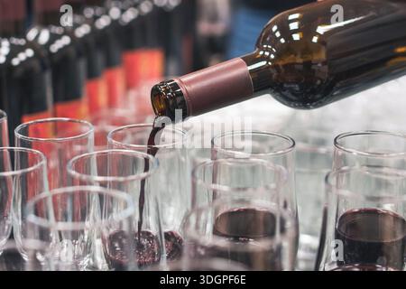 Vino rosso versato in più bicchieri durante un evento. Foto Stock
