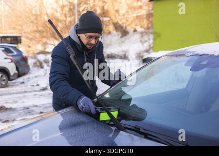 Un tizio sta ripulendo la neve da un'auto. Foto Stock