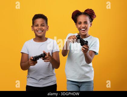 Emotivo fratello afroamericano e sorella con i joystick Foto Stock