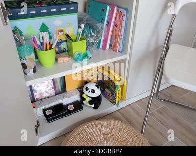 Nuovi giocattoli per bambini moderni in un armadietto bianco sullo scaffale. Pulizia e conservazione a casa. Design e ordine. Foto Stock