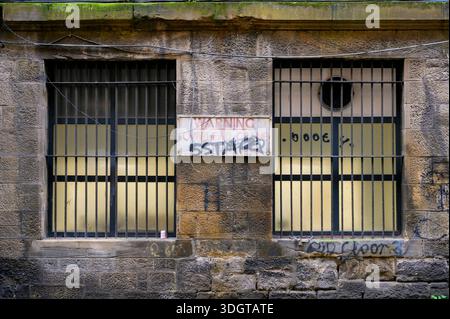 Finestre con barre in un vecchio edificio in pietra, Regno Unito Foto Stock