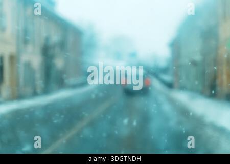 Visuale sfocata della guida in caso di forti nevicate attraverso il parabrezza dell'auto, messa a fuoco selettiva. Foto Stock