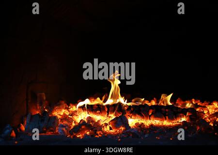 Scintille calde rosse che bruciano volano dal fuoco grande. Bel sfondo astratto sul tema del fuoco. Carboni brucianti, particelle infiammate che volano contro la colpa Foto Stock