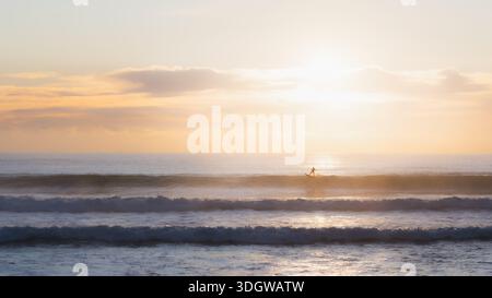 Silhouette di un surfista che strizza un'onda a Burleigh Heads Beach all'alba vicino a Surfers Paradise, Gold Coast, Queensland, Australia. Foto Stock