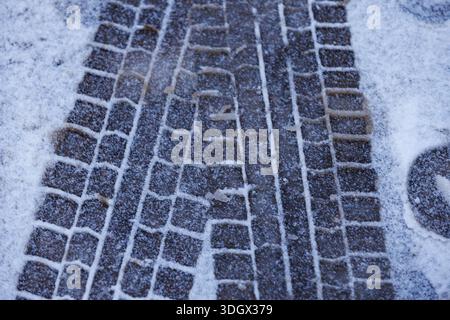Gli pneumatici dell'auto si muovono sulla neve fresca. Primo piano delle tracce degli pneumatici delle auto impresse sulla neve fresca sul fondo stradale, sulla struttura stradale invernale e sul concetto di trasporto. Foto Stock