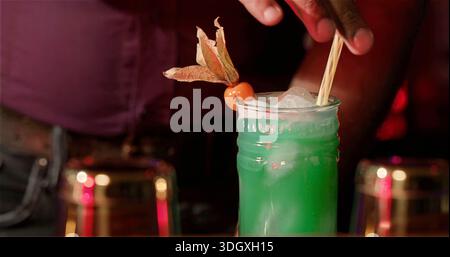Scena energetica con cocktail verde sormontato da Physalis e Straw in Climate of Neon Lights Foto Stock