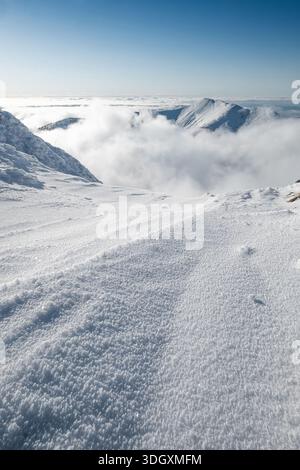 Cima del monte Maly Krivan a 1668 m di altitudine visibile su nuvole illuminate dal sole luminoso. Vista su Velky Krivan durante la stagione invernale di fine gennaio. Ha chiamato Mala Fatra Foto Stock