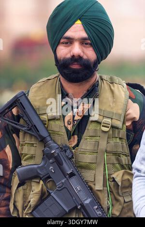 Soldato sikh in turbante verde con uniforme mimetica e giubbotto tattico con fucile, India, Delhi, 29 gennaio 2024 Foto Stock