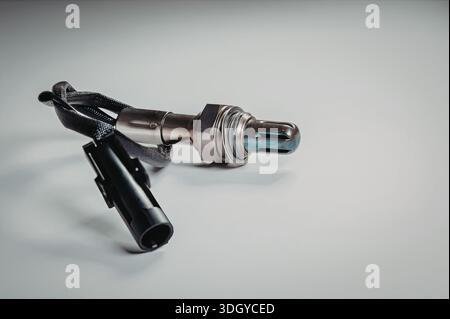 L'immagine mostra una vista ravvicinata di un connettore elettronico collegato a un filo. Il connettore è metallico con una forma cilindrica ed è dotato di un connettore metallico Foto Stock