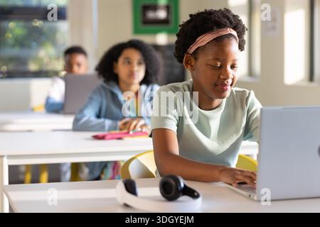 Studenti afroamericani che lavorano su laptop e cuffie argentate in classe, spazio copia Foto Stock