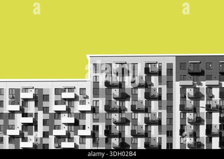 Moderno edificio di appartamenti con ripetitivi balconi in stile geometrico minimalista. La facciata monocromatica contrasta nettamente con uno sfondo giallo brillante Foto Stock