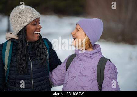 Due allegre donne che si divertono a fare una divertente escursione invernale nella natura Foto Stock