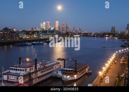 Inghilterra, Londra, Full Moon Over Docklands e Canary Wharf Skyline di notte Foto Stock
