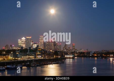 Inghilterra, Londra, Full Moon Over Docklands e Canary Wharf Skyline di notte Foto Stock