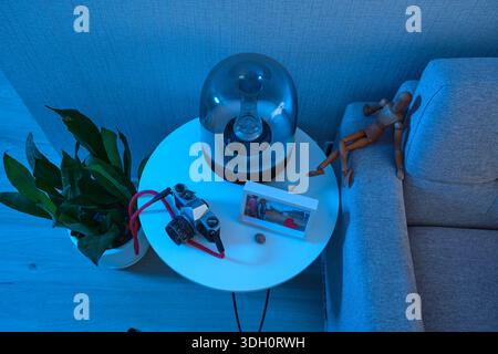 Moderno angolo soggiorno illuminato da una luce blu fredda, caratterizzato da vari oggetti decorativi Foto Stock