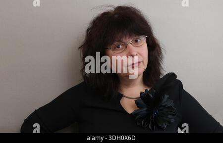 Ritratto in studio di una donna con gli occhiali. Una donna anziana e poderosa con occhiali, una camicetta nera con un grande fiocco e una bella acconciatura Foto Stock