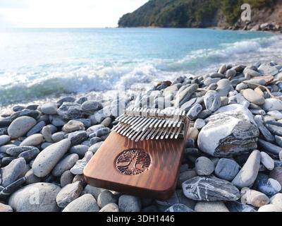 Strumento musicale Kalimba sulle pietre via mare. La natura vicino alle montagne, alla musica e alla meditazione. Relax e salute mentale. Foto Stock