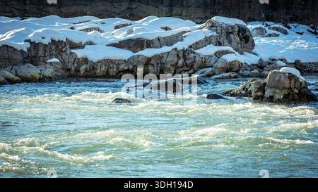 Vista dettagliata del flusso del fiume freddo e delle rocce innevate a Kutaisi. Texture naturale, movimento e luce invernale per creare uno sfondo stagionale pulito Foto Stock