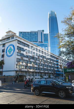 Una strada cittadina a Santiago, Cile, con un edificio medico in primo piano e la Gran Torre Santiago che sorge dietro uffici moderni. Foto Stock
