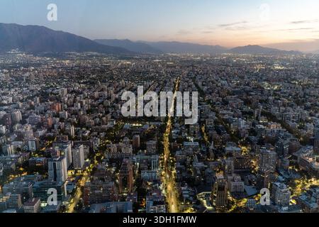 Una vista al crepuscolo di Santiago, Cile, fotografata dal Costanera Center, che mostra le strade della città illuminate di notte e le colline circostanti. Foto Stock