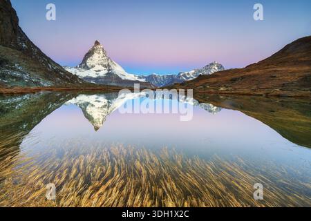 Cervino a 4, 478â€¯m, simbolo iconico della Svizzera, riflesso nel lago Riffelsee all'alba in autunno, Zermatt, Vallese, Svizzera Foto Stock