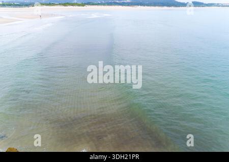 Vista ad alto angolo di una splendida spiaggia di sabbia e acque cristalline dell'oceano con onde dolci. Foto Stock