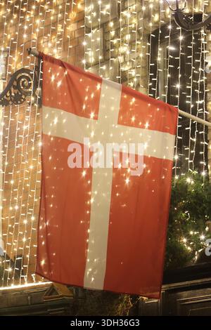 Dublino, Irlanda - 14 gennaio 2026: Una bandiera nazionale danese illuminata da centinaia di piccole luci è appesa al muro di un pub a Temple Bar in una mattinata buia nella città di Dublino che raffigura scene di strada nella capitale irlandese Foto Stock