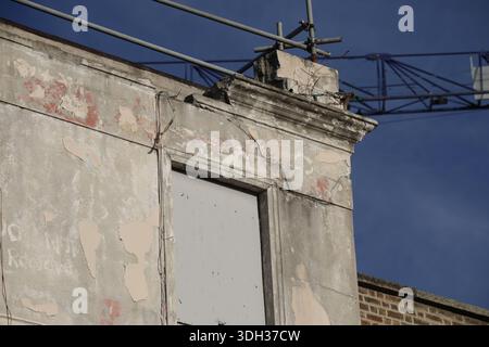 Dublino, Irlanda - 16 gennaio 2026: Vista ravvicinata di una facciata di un edificio fatiscente con intonaco rotto e finestra a bordo vista sul Quays nella città di Dublino Foto Stock