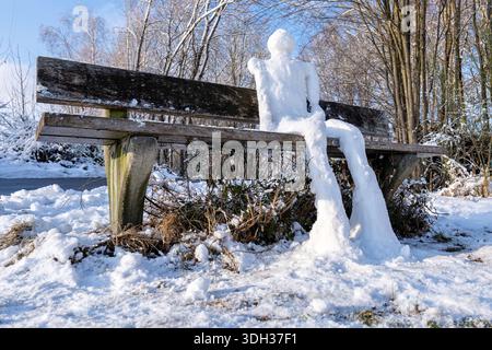 pupazzo di neve umanoide seduto su una panchina Foto Stock