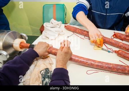Le mani delle donne fanno il chorizo fatto in casa su un tavolo bianco durante la tradizionale macellazione di maiali in Spagna. Foto Stock