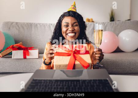 Vista frontale di Black Woman che offre regalo di compleanno per il notebook al chiuso Foto Stock