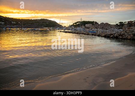 Il tramonto dorato illumina il porto di Port de Soller, le barche e la città costiera di Maiorca. Foto Stock