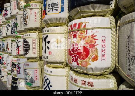 ISE, Giappone - 29 ottobre 2023: Vista ravvicinata di botti di sake dipinte impilate con scritte giapponesi, illustrazioni colorate e legature di corda all'aperto. Foto Stock